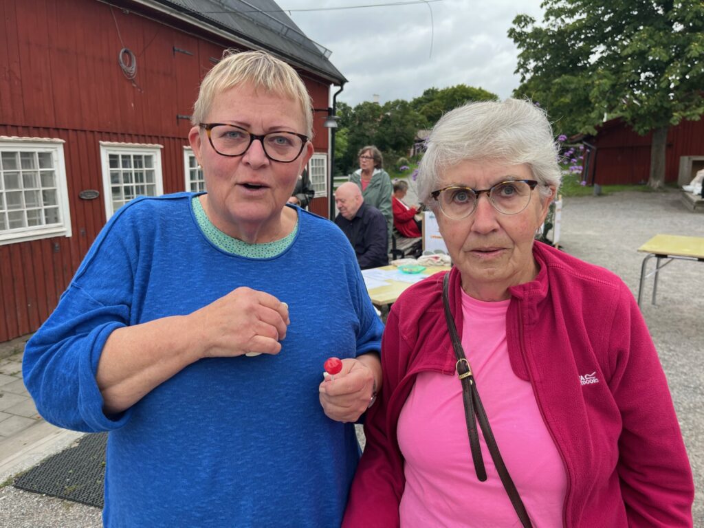 Två äldre damer, en i blått och en i rött och rosa.