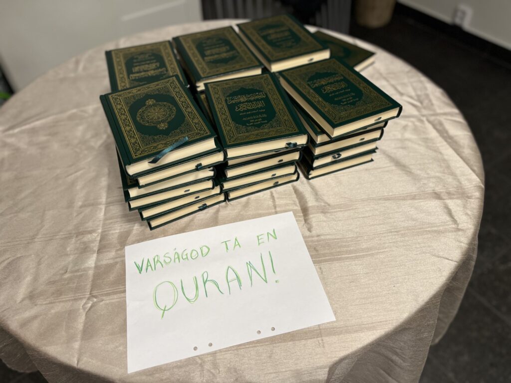 bild på quranen i högar och en lapp med texten "varsågod ta en quran"